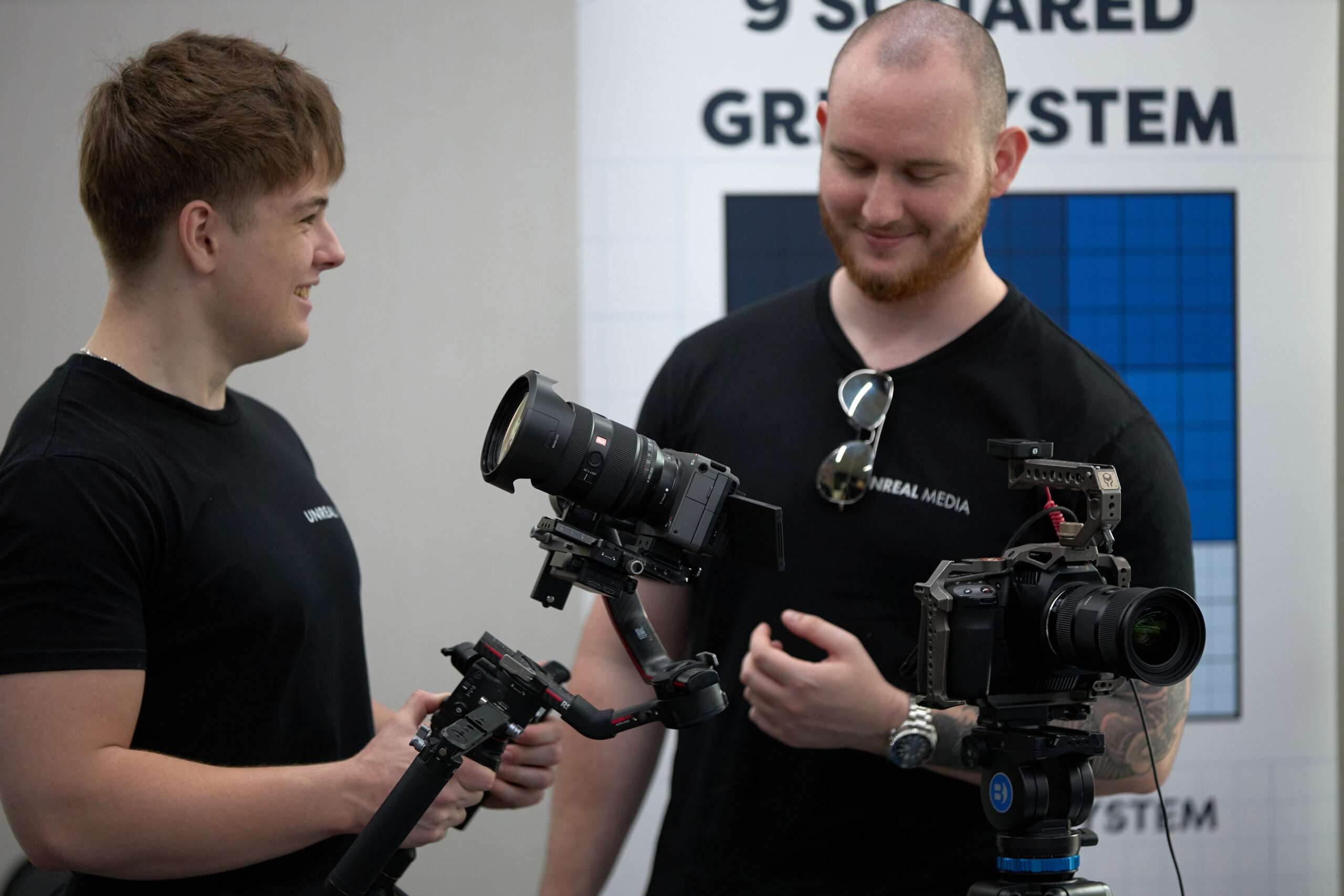 Jakob Quinn, owner of Unreal Media (right), discussing camera gear with a team member during a Brisbane video production setup — part of a behind-the-scenes look at what goes into professional video projects.