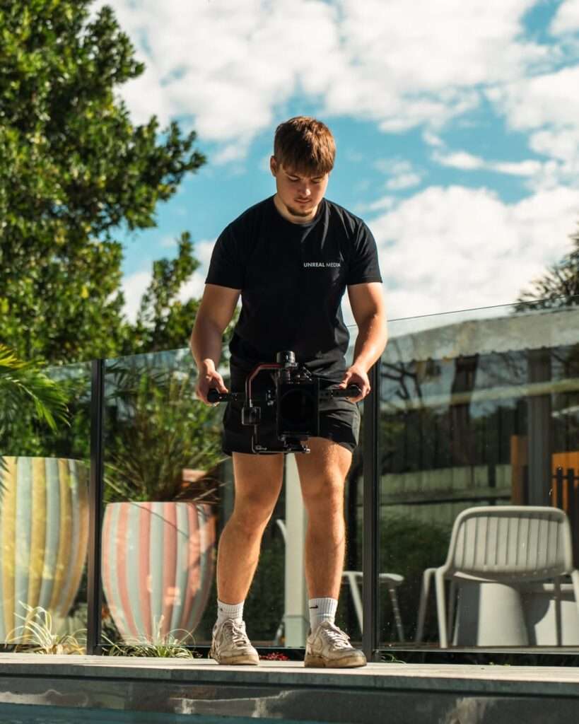 Videographer from Unreal Media filming poolside content for a local business, showcasing how Brisbane businesses use video to grow through strategic visual storytelling and high-impact brand content.